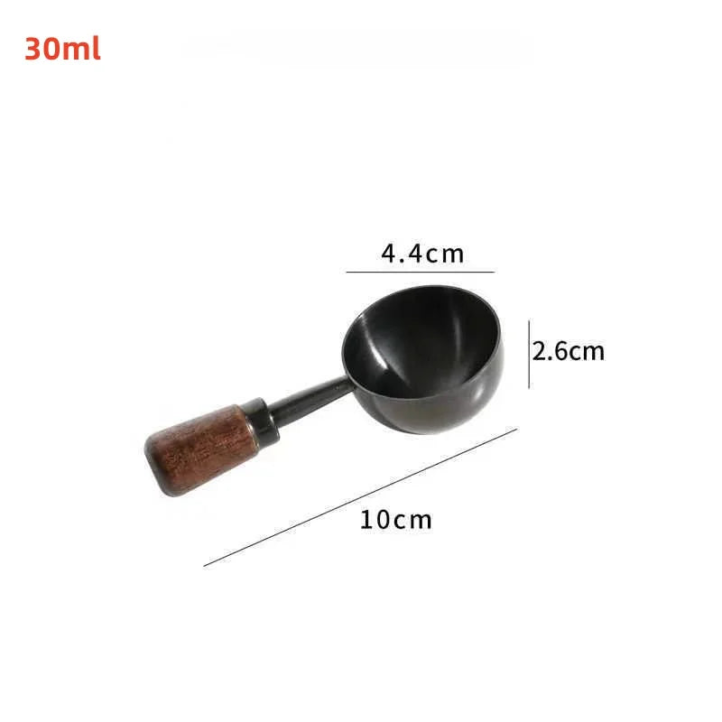 A small black metal scoop or ladle with a brown wooden handle, shown on a plain white background.