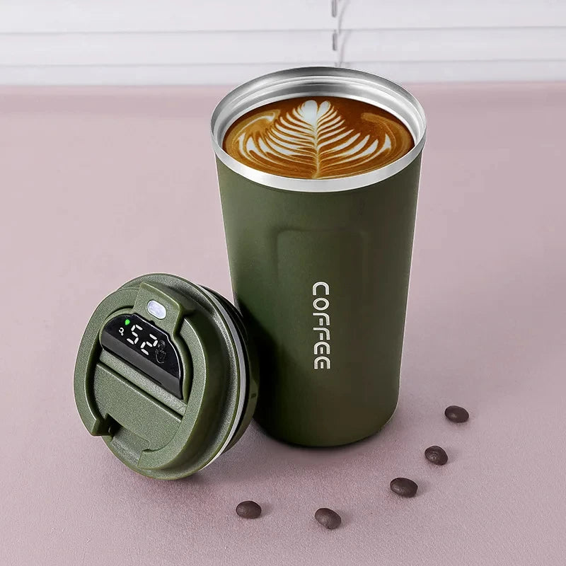 Green insulated coffee tumbler with a digital temperature display on a pink surface.