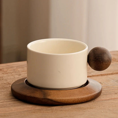 White ceramic cup with wooden handle and base on a wooden surface