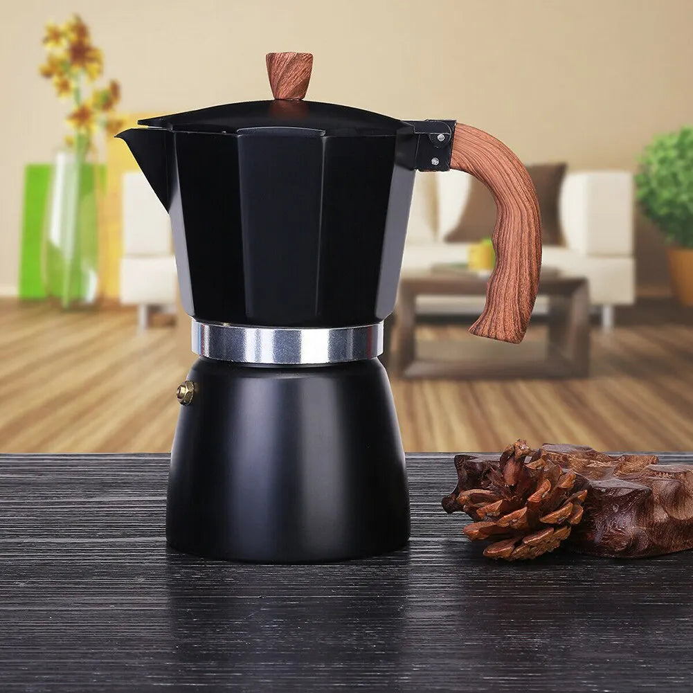 Black espresso maker with wooden handle on a wooden surface, blurred indoor background