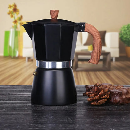 Black espresso maker with wooden handle on a wooden surface, blurred indoor background