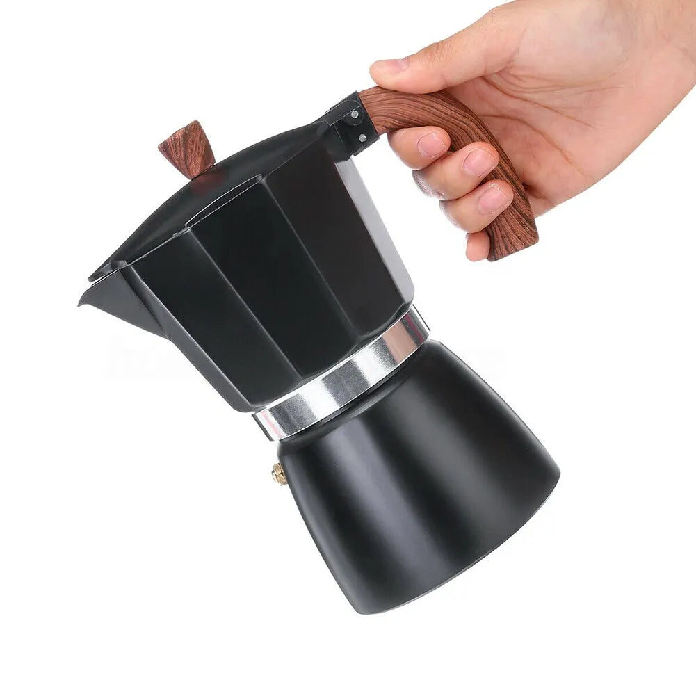 Black coffee maker with wooden handle held by a hand on a white background