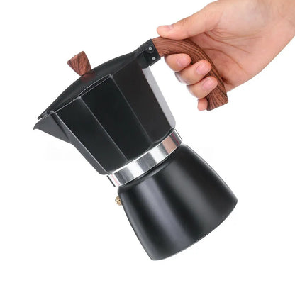 Black coffee maker with wooden handle held by a hand on a white background