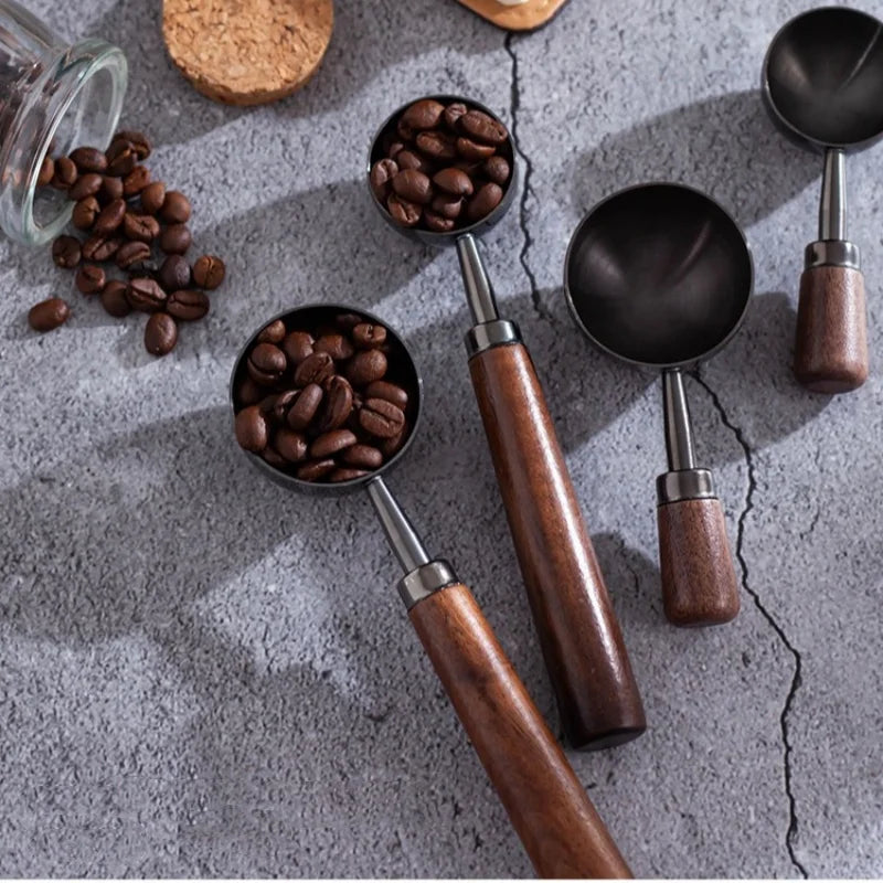 Wooden coffee scoops with beans on a gray surface