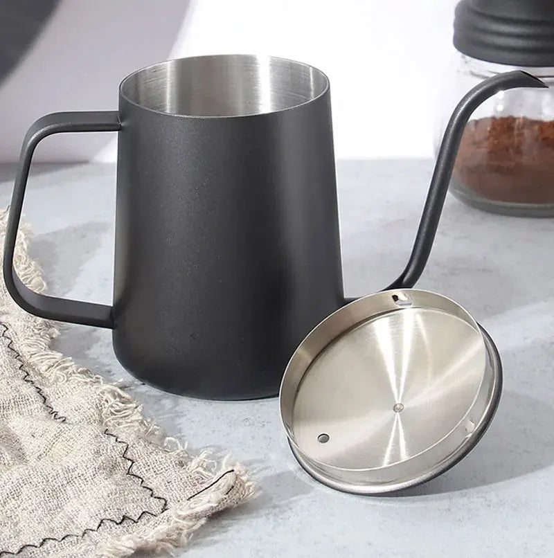 Matte black pour-over coffee mug with a stainless steel interior and spout, shown alongside its stainless steel lid on a light gray surface.