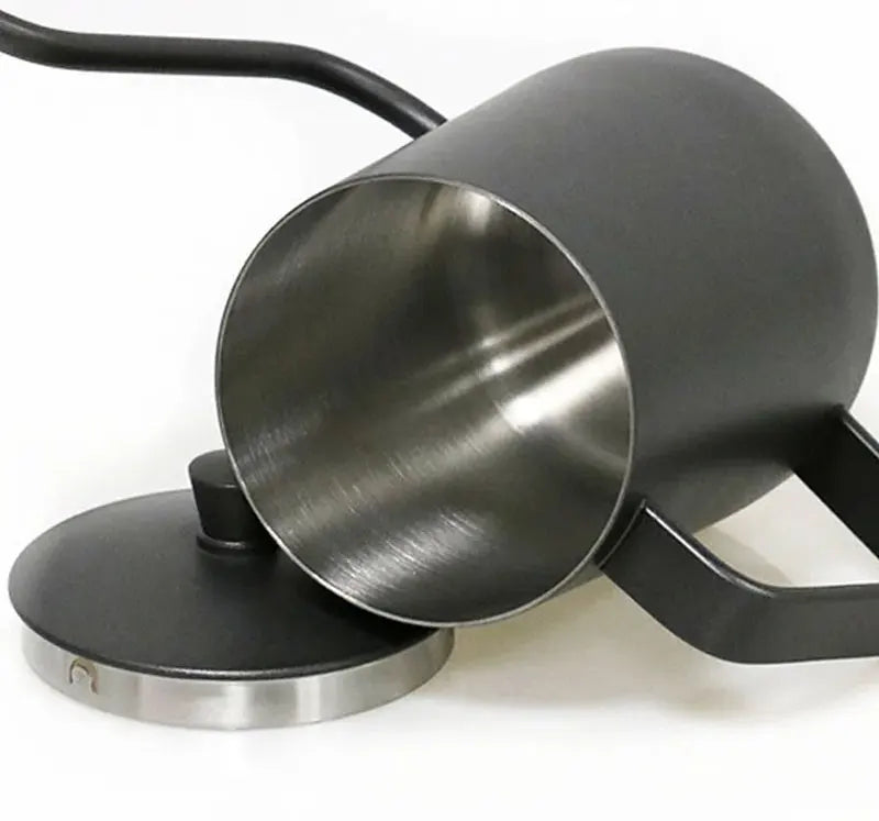 A matte black metal pitcher with a brushed stainless steel interior, shown tipped over with its matching lid resting beside it on a white background.