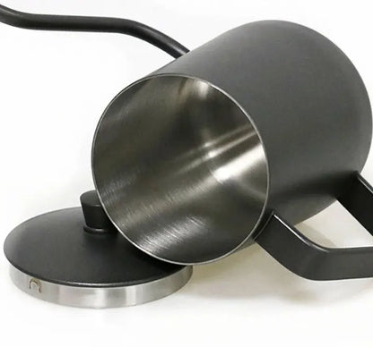 A matte black metal pitcher with a brushed stainless steel interior, shown tipped over with its matching lid resting beside it on a white background.