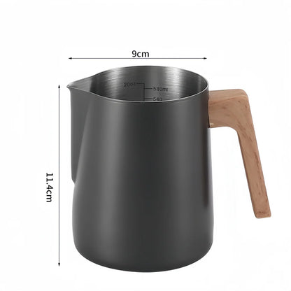 A matte dark gray milk pitcher with a light wood handle and stainless steel interior, shown with dimension lines indicating 9 cm width and 11.4 cm height.