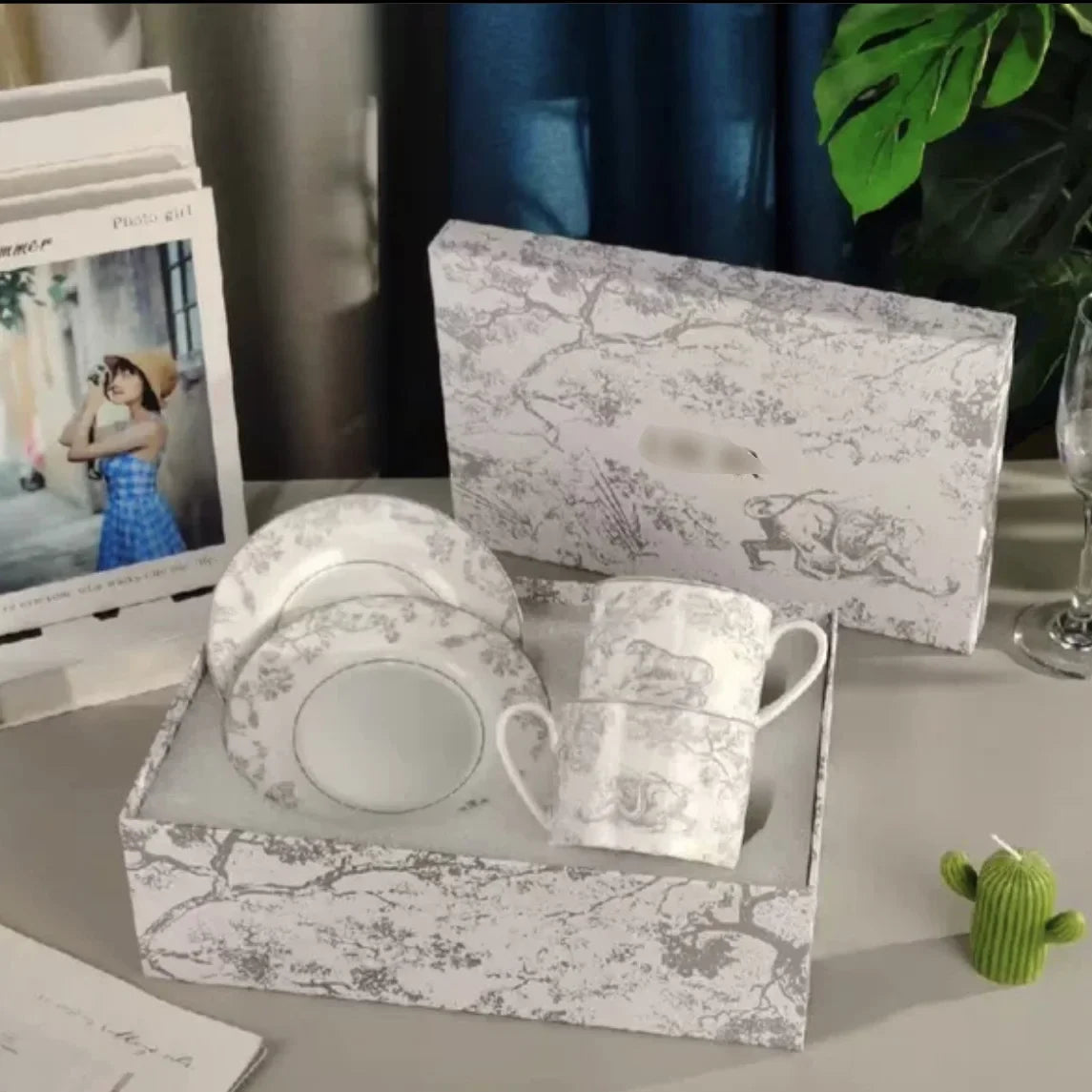 Ceramic coffee set with matching packaging on a surface with a plant in the background