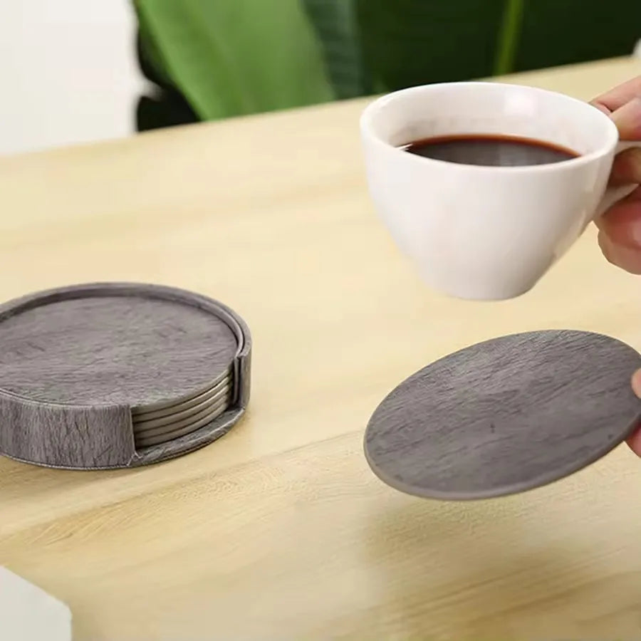 Set of gray coasters on a wooden table with a cup of coffee.