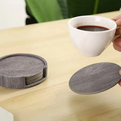 Set of gray coasters on a wooden table with a cup of coffee.