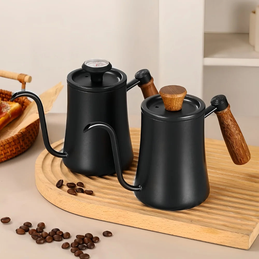 Two black coffee pots with wooden handles on a wooden tray with coffee beans.