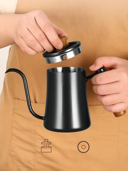 A matte black gooseneck kettle with a stainless steel rim and cork handles, being opened by a person wearing a tan apron.