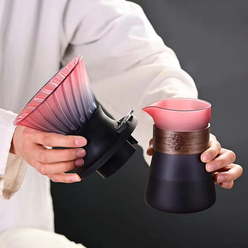 Person holding a pink and black coffee brewing device against a dark background