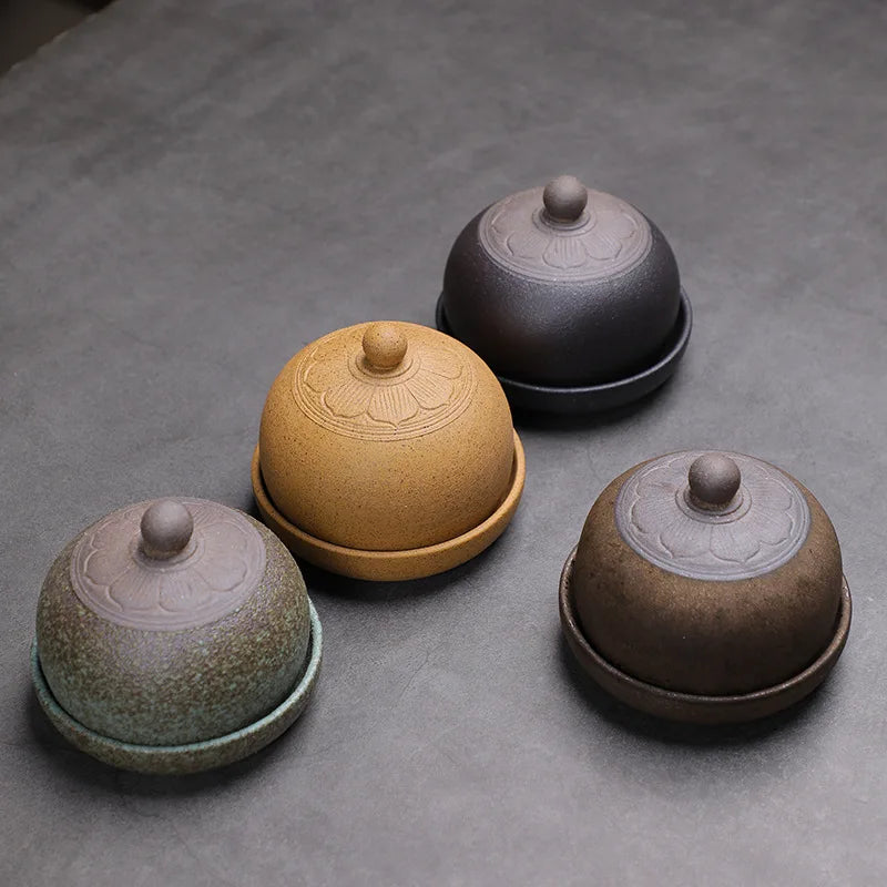 Four ceramic containers with lids on a gray surface