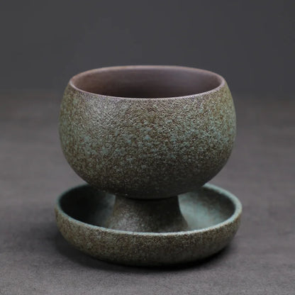 Green ceramic cup and saucer set on a dark gray background