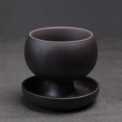 Black ceramic cup and saucer on a dark gray background
