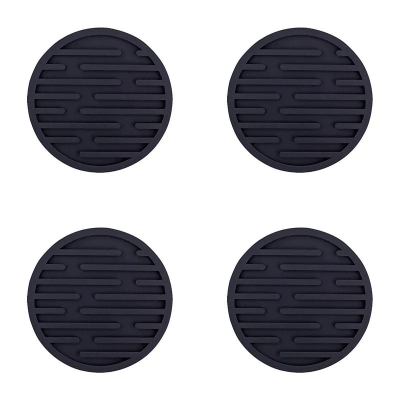 Four black silicone coasters with a textured surface on a white background
