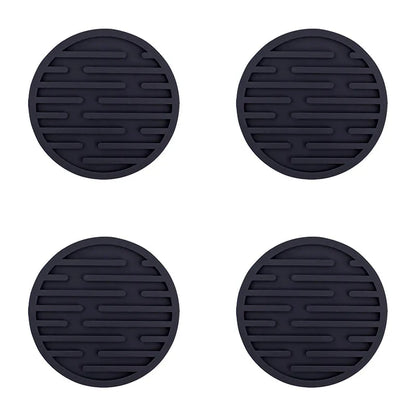 Four black silicone coasters with a textured surface on a white background