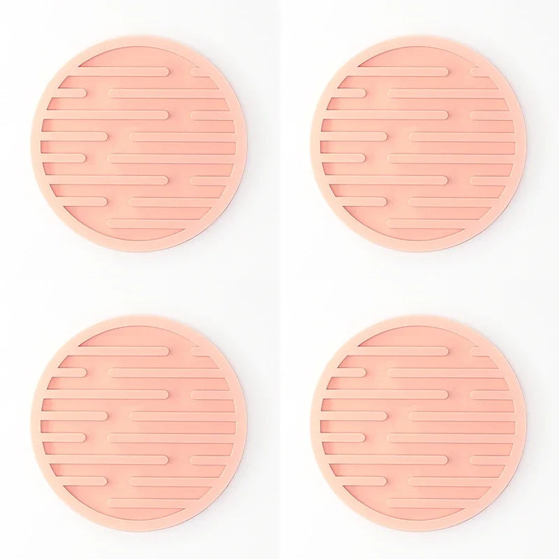Four pink silicone trivets with textured design on a white background