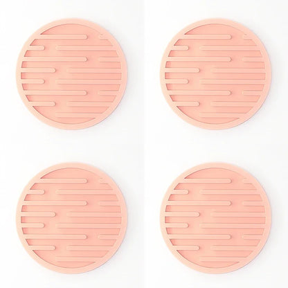 Four pink silicone trivets with textured design on a white background