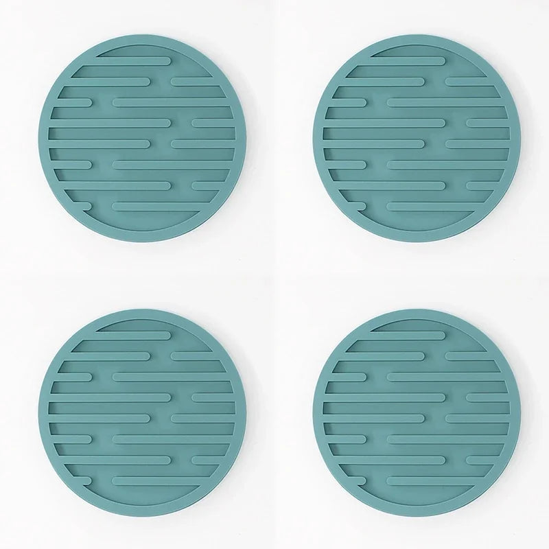 Four teal silicone trivets on a white background