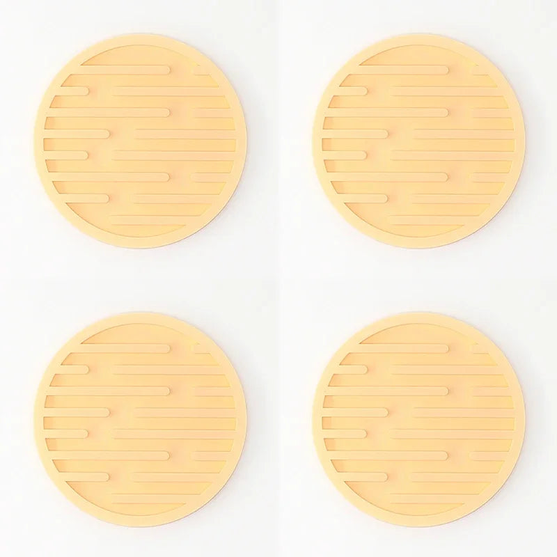 Four yellow trivets with textured surface on a white background