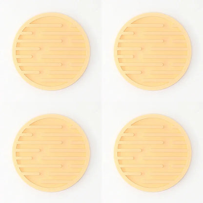Four yellow trivets with textured surface on a white background