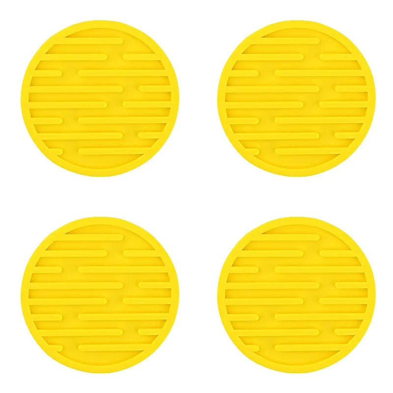 Four yellow circular silicone mats with a textured surface on a white background