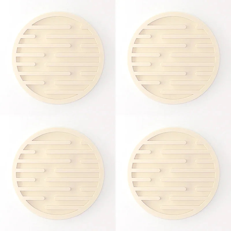 Four round beige coasters with a textured surface on a white background