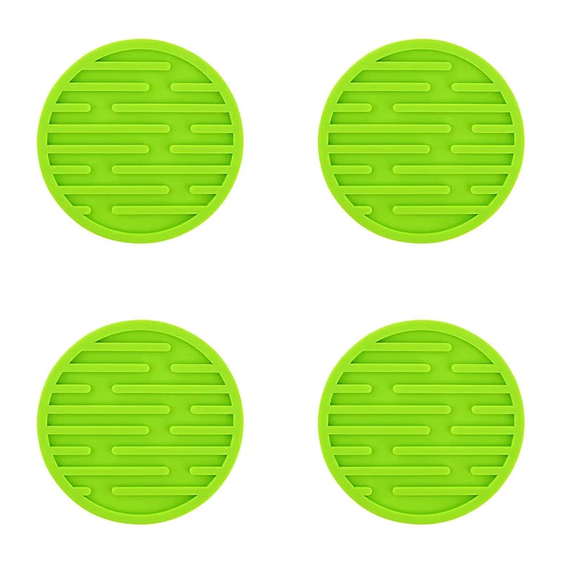 Four green silicone trivets with textured surface on a white background