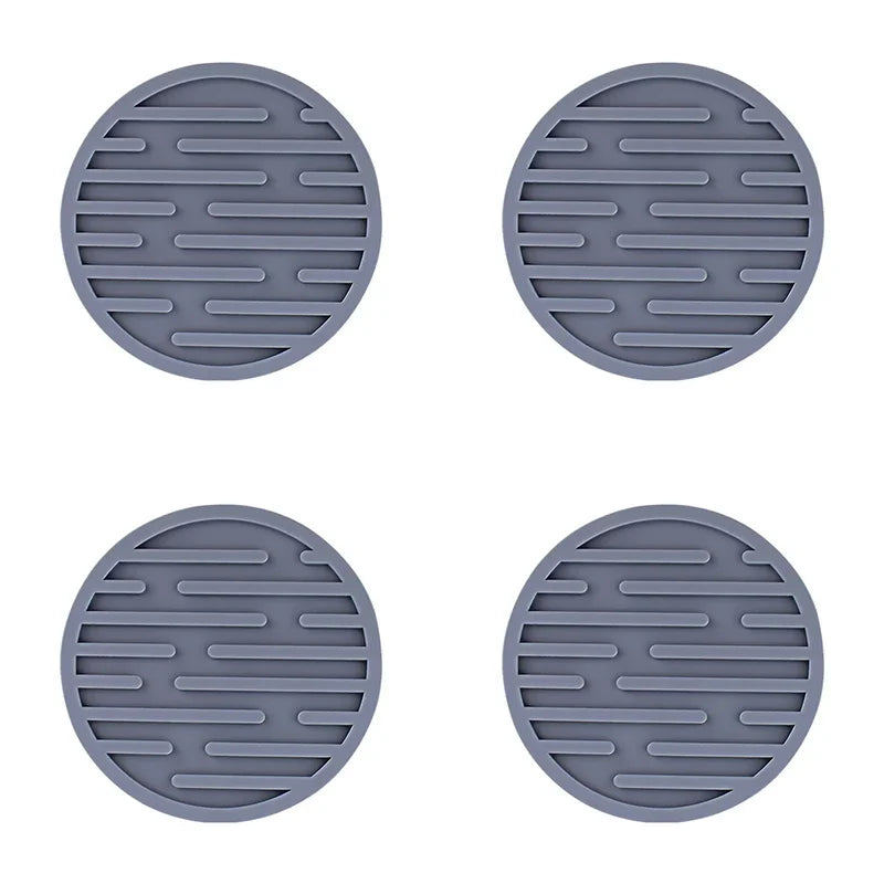 Four gray silicone trivets with textured surface on a white background