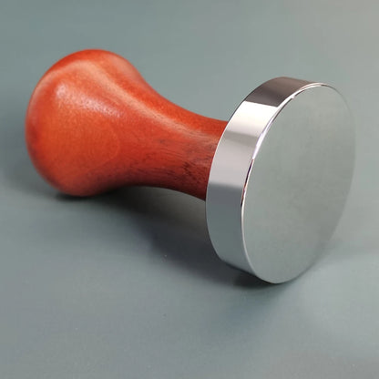 Red wooden tamp with silver metal base on a gray background