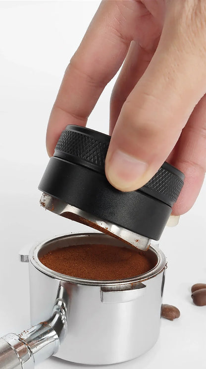 Hand using a coffee tamp to compress ground coffee into a filter basket.