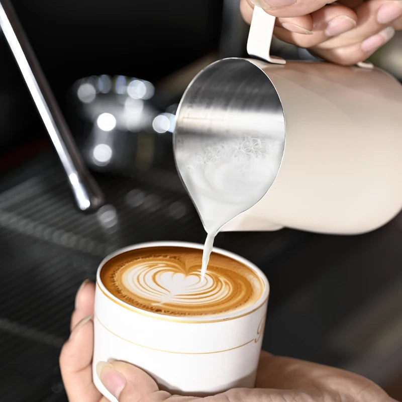 Person pouring milk into a cup of coffee with latte art.