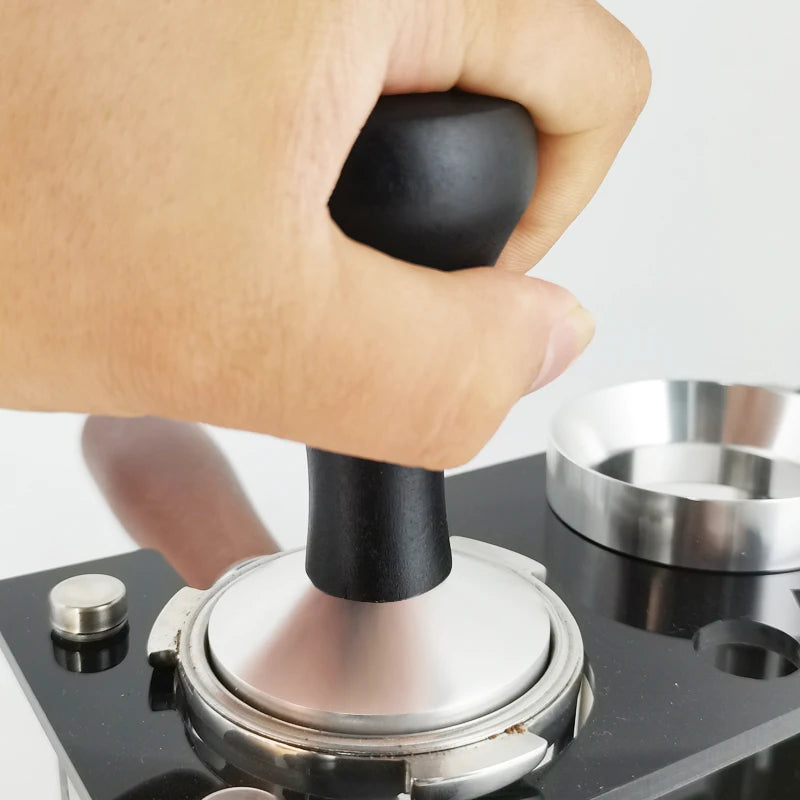 Hand using a coffee tamp to compress ground coffee into a portafilter basket.
