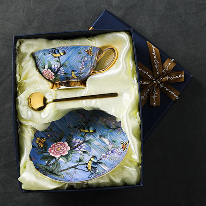 Decorative teacup, saucer, and spoon set with floral and bird design in a gift box.