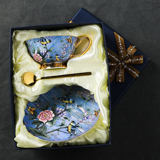 Decorative teacup, saucer, and spoon set with floral and bird design in a gift box.