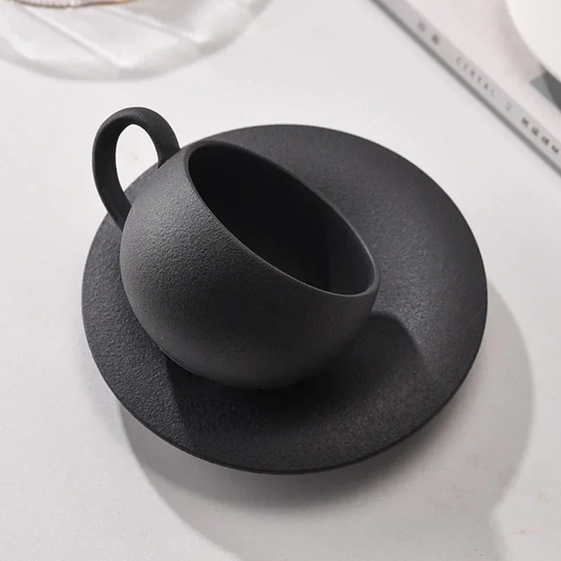 Black ceramic cup and saucer on a white surface