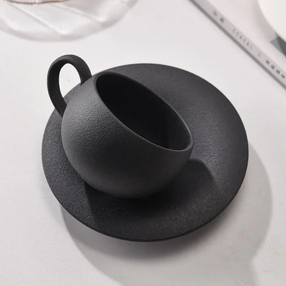 Black ceramic cup and saucer on a white surface