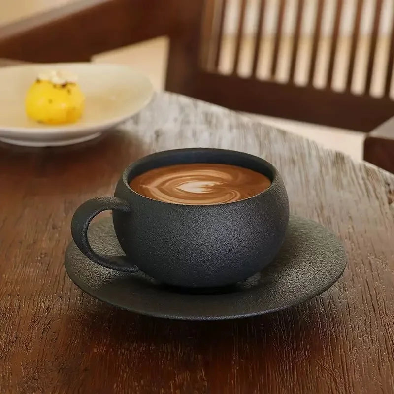Black textured coffee cup with a latte art design on a wooden table.