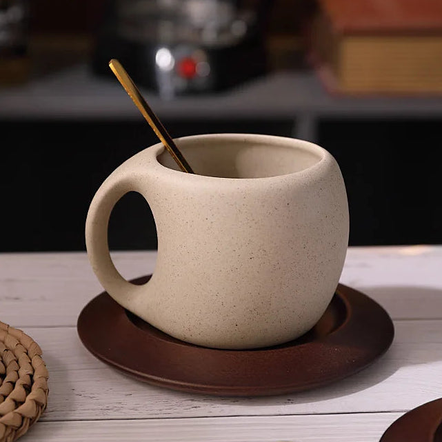 Beige ceramic mug with a wooden spoon on a brown coaster on a wooden surface.