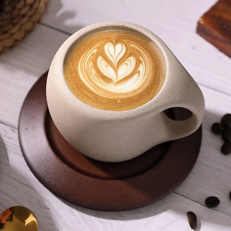 Ceramic coffee cup with latte art on a wooden coaster