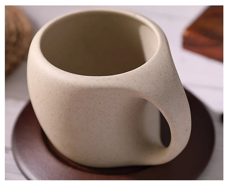 Beige ceramic cup with handle on a matching saucer against a neutral background
