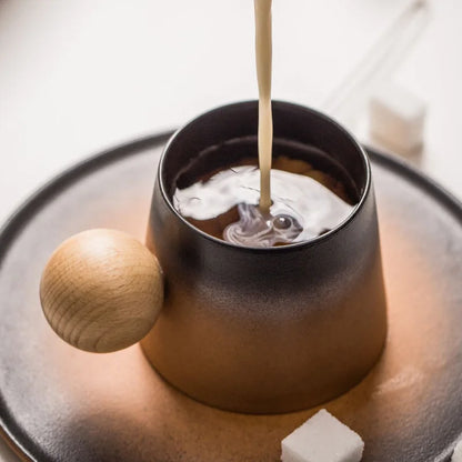 Ceramic mug with wooden handle being filled with a liquid on a matching plate.
