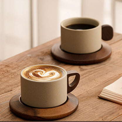 Two coffee cups on wooden coasters with a heart-shaped design in the foam.