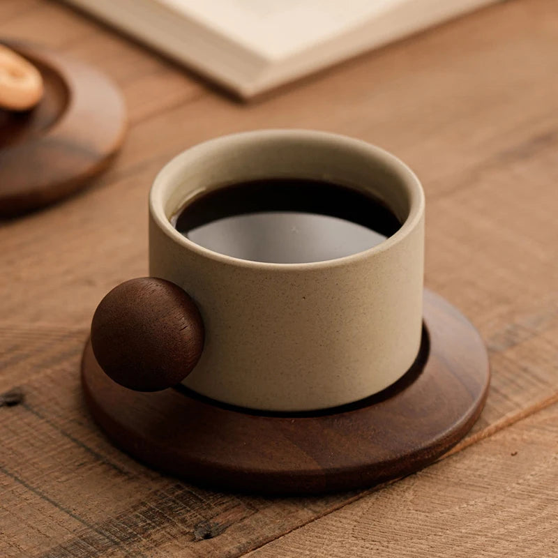 Ceramic cup with dark liquid on a wooden coaster on a wooden surface