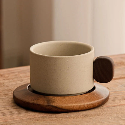 Beige ceramic coffee cup with wooden handle and coaster on a wooden surface