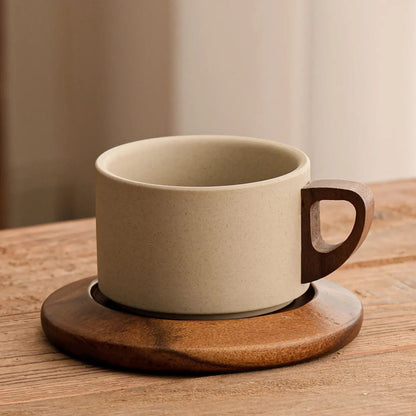 Beige ceramic coffee cup with wooden handle on a wooden coaster, placed on a wooden surface.