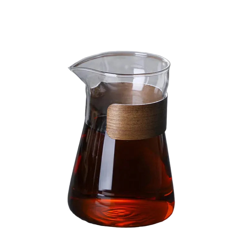 Glass carafe with wooden lid filled with dark liquid on a gray surface